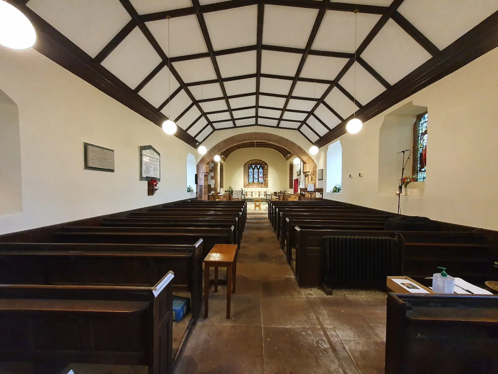 Inside a small church, looking down the aisle between wooden pews